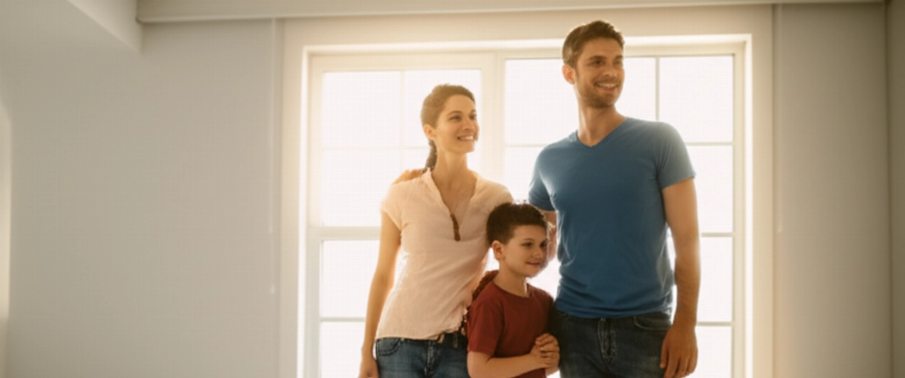 A happy Caucasian family smiles in a bright room of their new home, symbolizing a successful move and a new beginning.